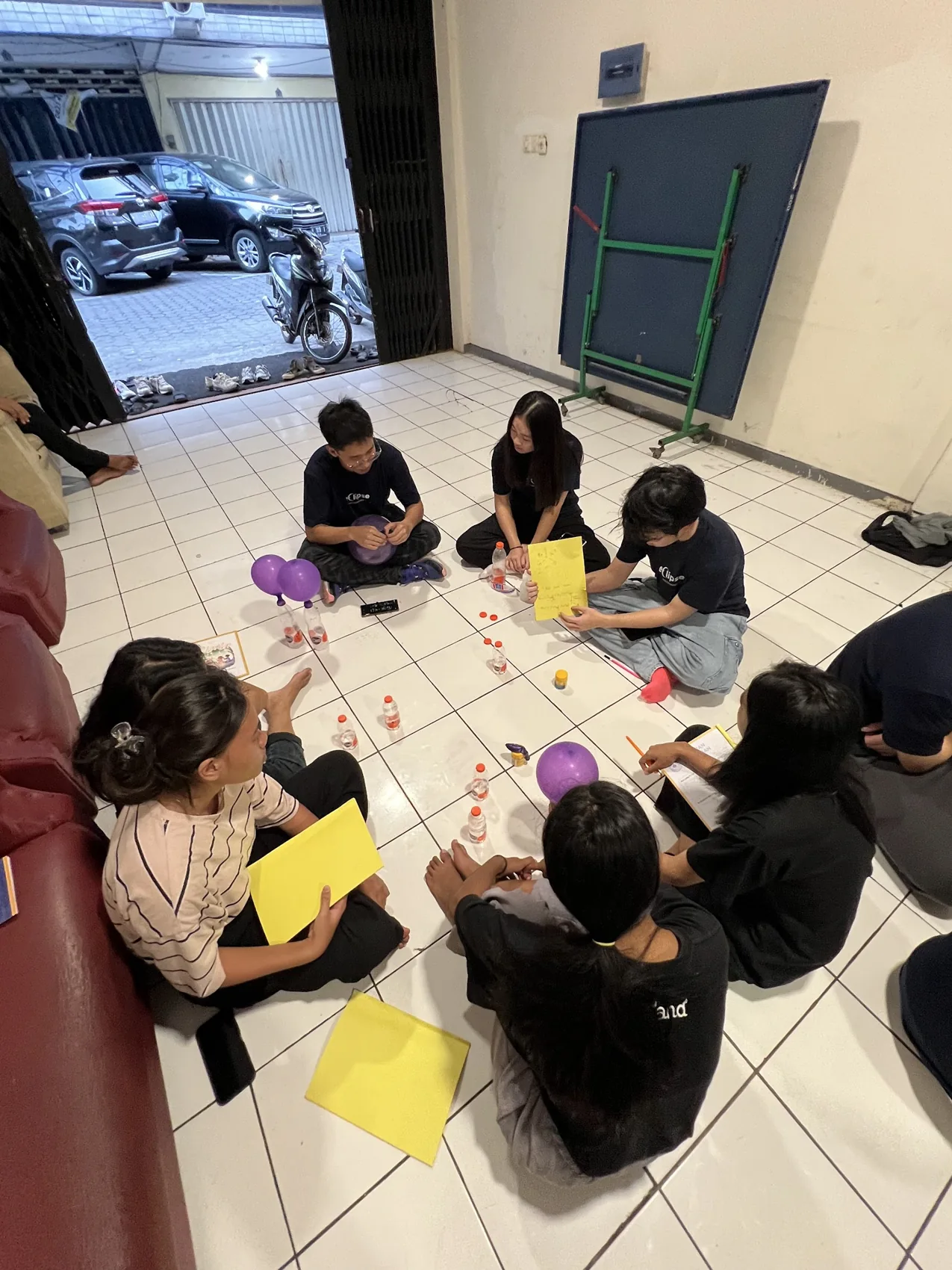 An overhead view of a group making paper activities on a tiled floor.