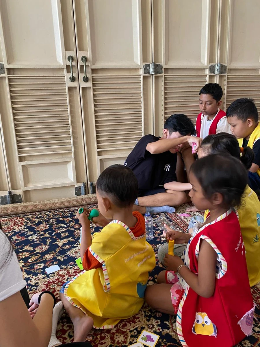 A volunteer and children exploring an activity together