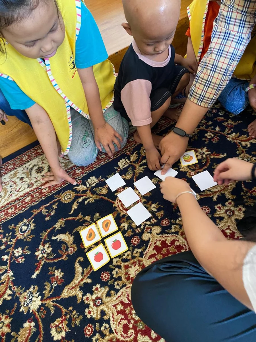 Children and volunteers playing a fruit-card matching activity